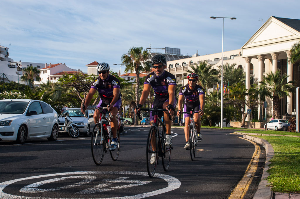 Radfahrer in San Miguel de Abona, Teneriffa, auf einer Straße mit Gebäuden und Palmen.