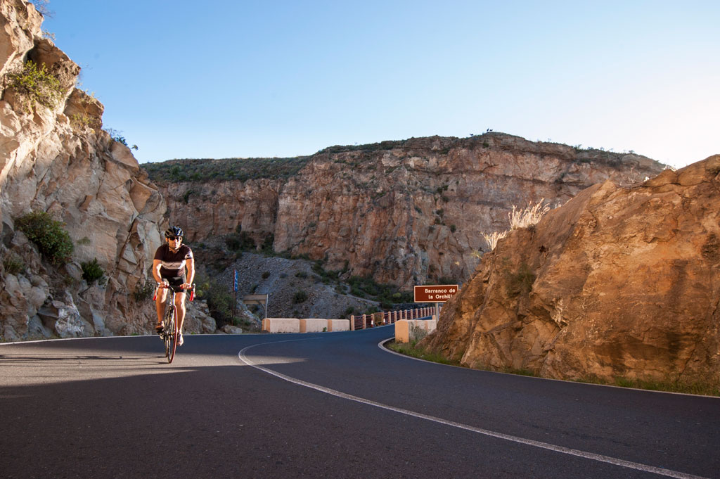 Radfahrer auf der Straße des Barranco de la Orchilla, Teneriffa, nahe einer Klippe.