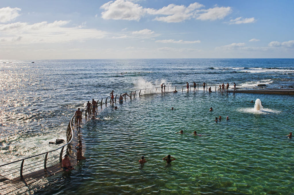 Die Menschen schwimmen in einem natürlichen Pool am Meer auf Teneriffa.