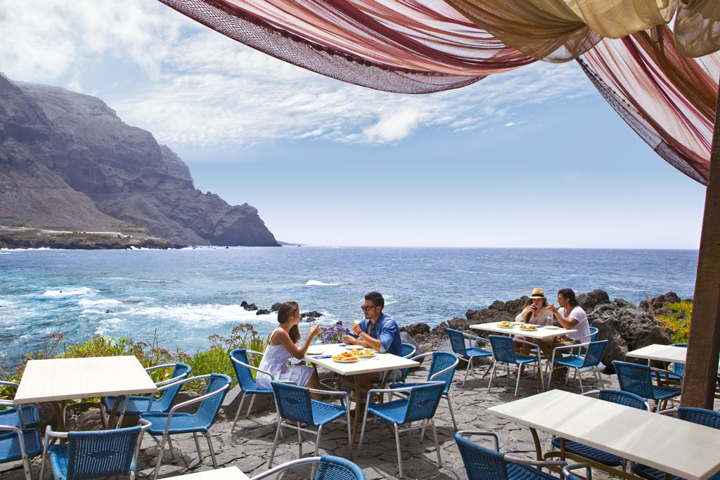 Strandterrasse auf Teneriffa mit Menschen, die unter klarem Himmel essen.