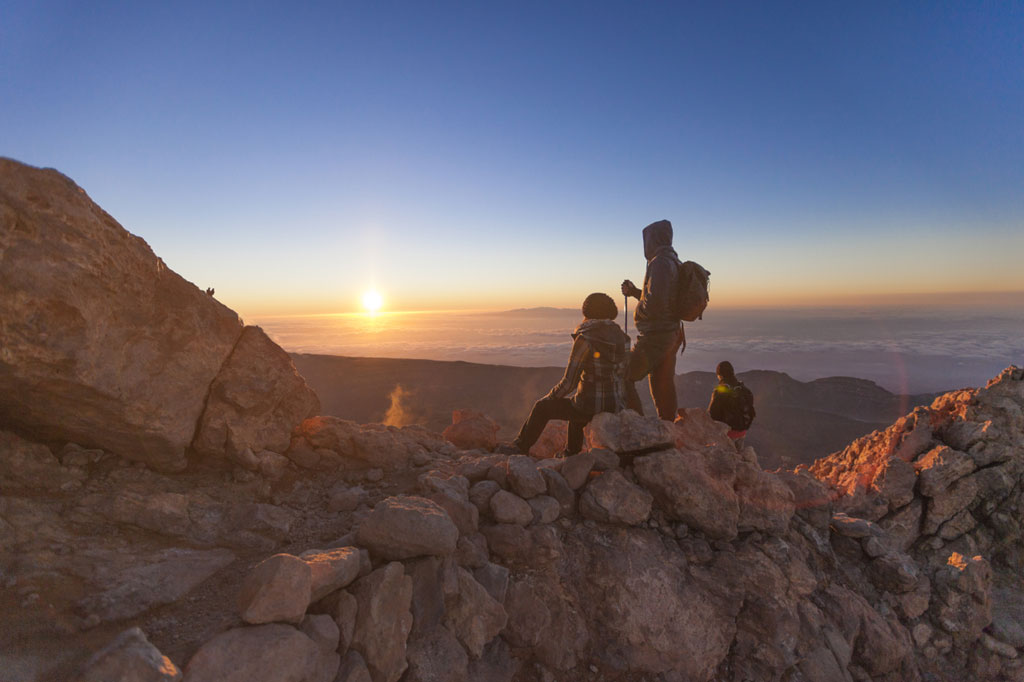 Wanderer beobachten den Sonnenaufgang vom Pico del Teide auf Teneriffa.