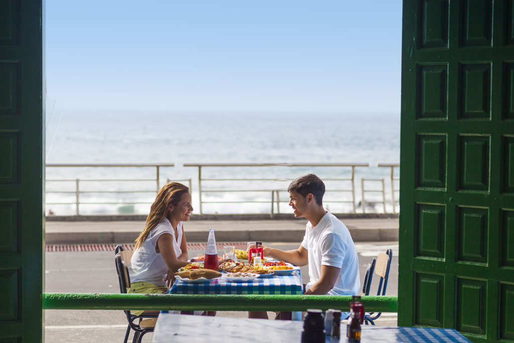 Ein Paar isst auf einer Terrasse mit Blick auf das Meer auf Teneriffa.