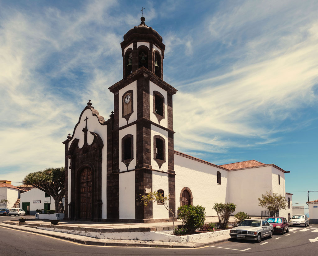 Kirche in Garachico, Teneriffa, mit klarem Himmel und Bäumen ringsum.
