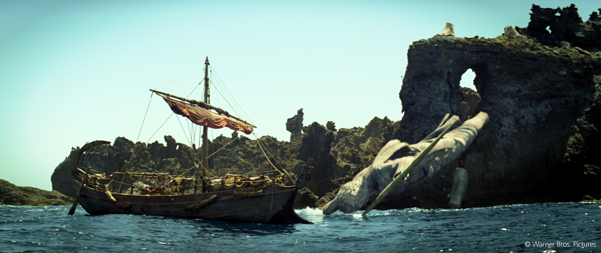 Ein Segelboot im Meer mit Felsen aus Los Cristianos im Hintergrund.
