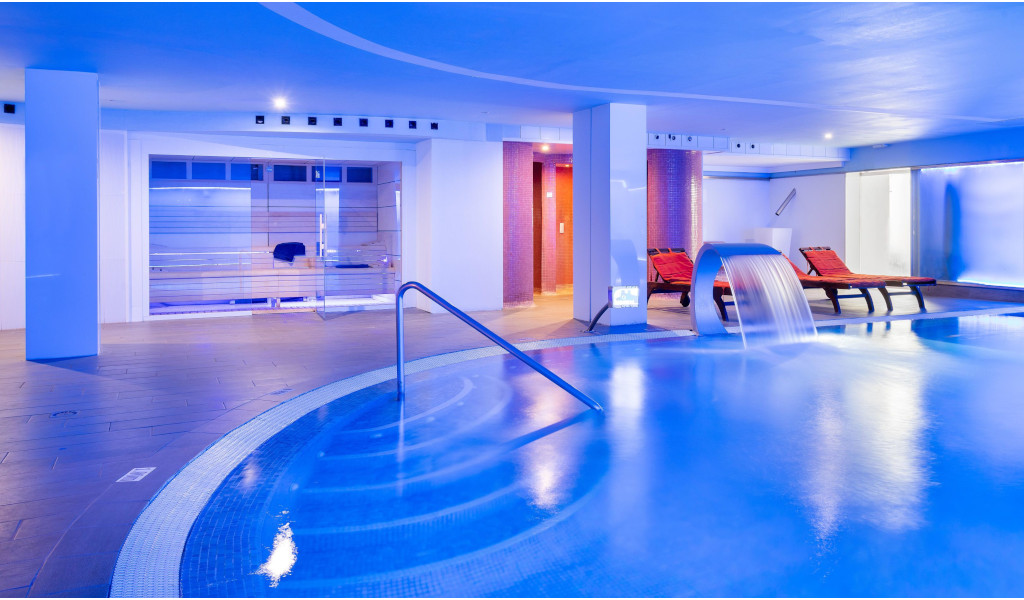 Hallenbad mit Wasserfall und Sonnenliegen im Tenerife Spa.