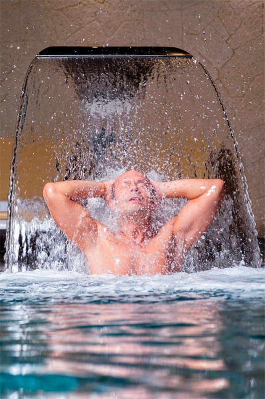 Person unter Wasserfall im Spa auf Teneriffa.