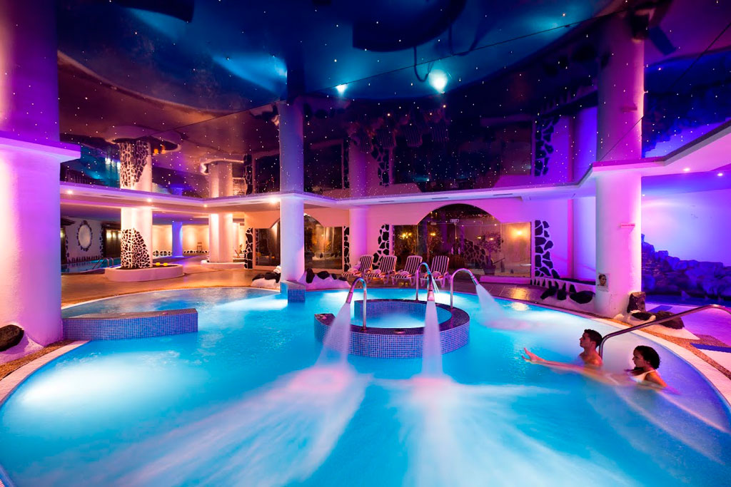 Erleuchtetes Innenbad in einem Spa auf Teneriffa, in dem zwei Personen entspannen.