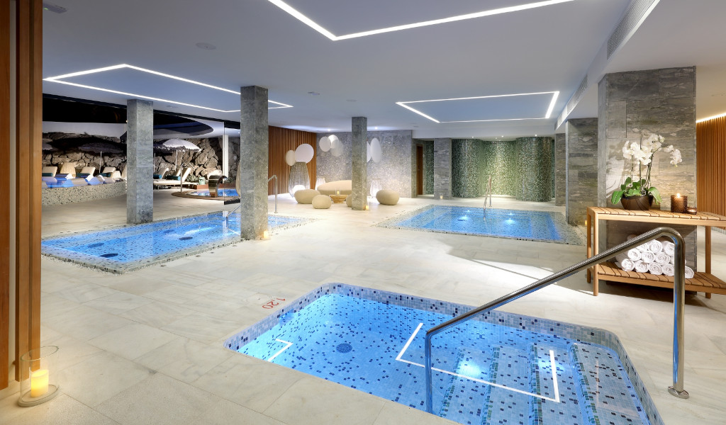 Hallenbad mit Jacuzzi in einem Spa auf Teneriffa, umgeben von Pflanzen und Lampen.