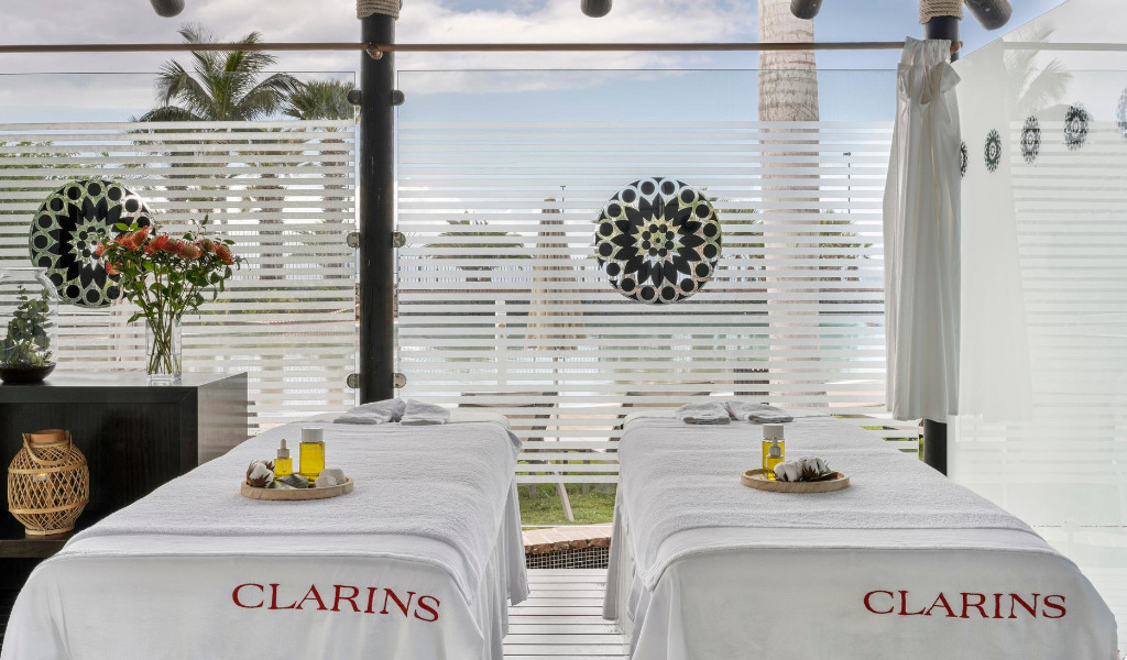Massagetisch mit Ölen im Clarins Spa auf Teneriffa, neben einem dekorierten Fenster.