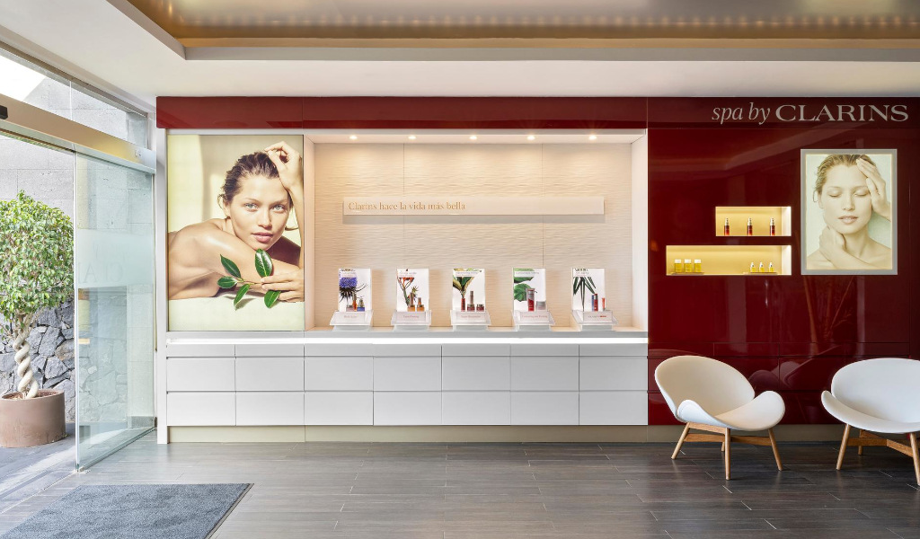 Empfang des Clarins-Spas auf Teneriffa mit Plakaten von Modellen und Produkten. Text: Clarins macht das Leben schöner.