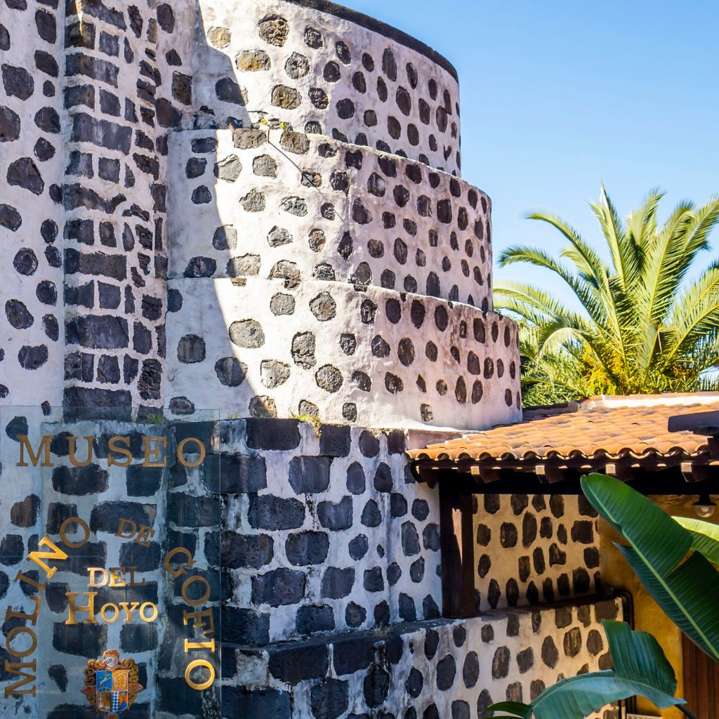Die Mühle Gofio del Hoyo auf Teneriffa mit Palmen im Hintergrund.