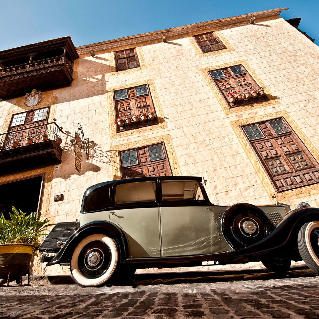 Oldtimer, der vor einem historischen Gebäude auf Teneriffa geparkt ist.