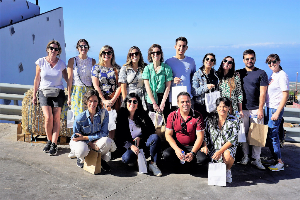 Eine Gruppe lächelnder Menschen vor dem Meer an einem Ort auf Teneriffa, mit Geschenktüten.