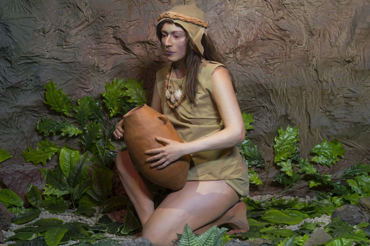 Frau in traditioneller Aborigines-Kleidung hält einen Tontopf auf Teneriffa.