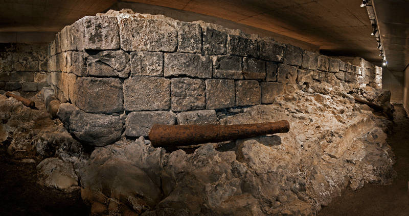 Die Ruinen einer historischen Mauer auf Teneriffa sind unter einem Betondach beleuchtet.