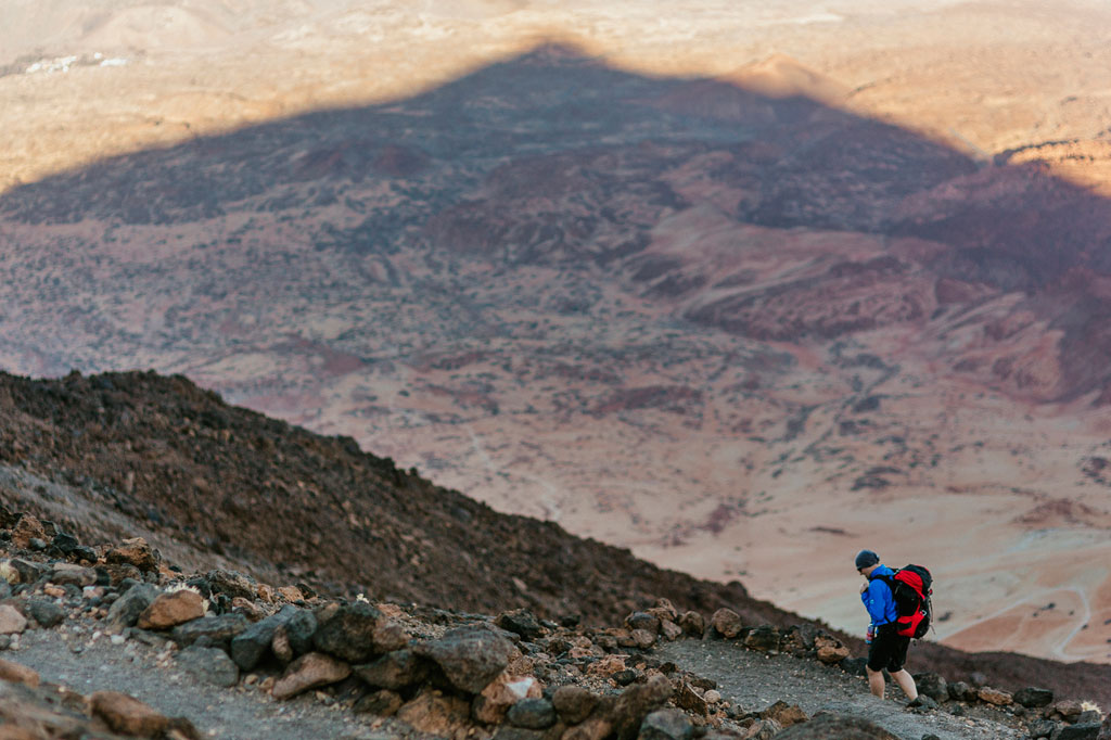Person, die auf einem felsigen Pfad auf dem Teide auf Teneriffa geht, mit trockener Landschaft im Hintergrund.