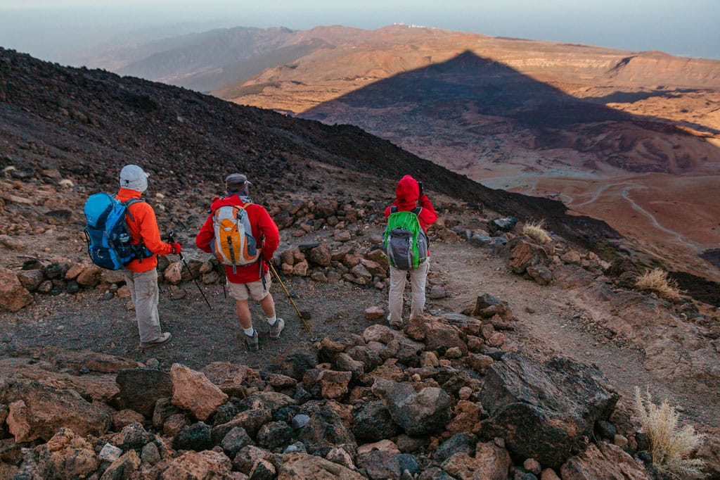 Drei Wanderer wandern auf felsigen Wegen im Nationalpark Teide auf Teneriffa.