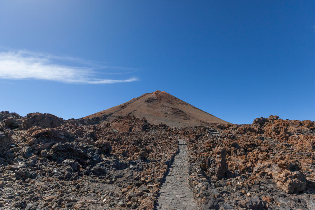 Ein Kieselpfad zum Teide-Berg auf Teneriffa unter blauem Himmel.
