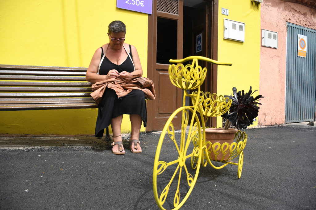 Frau sitzt auf einer Bank neben einem dekorativen Fahrrad auf Teneriffa.