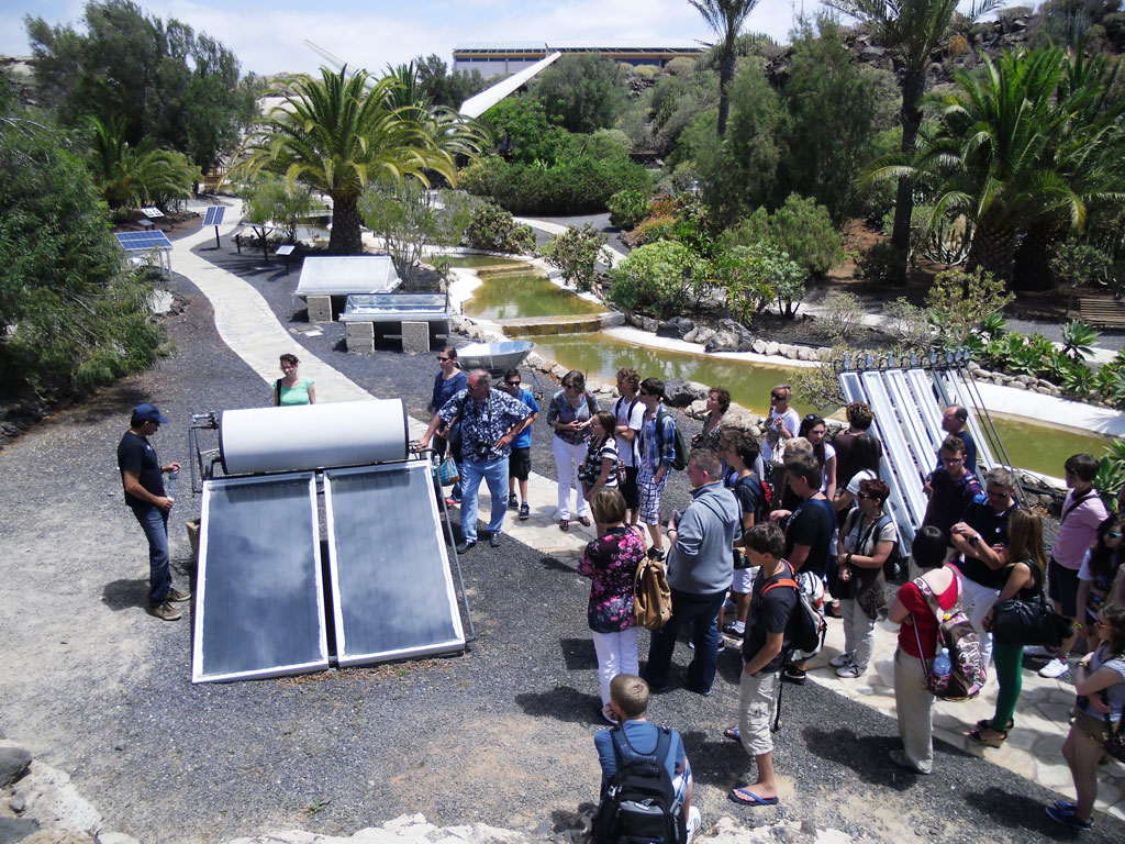 Eine Gruppe von Menschen, die Solarpanels in einem Park auf Teneriffa beobachtet.