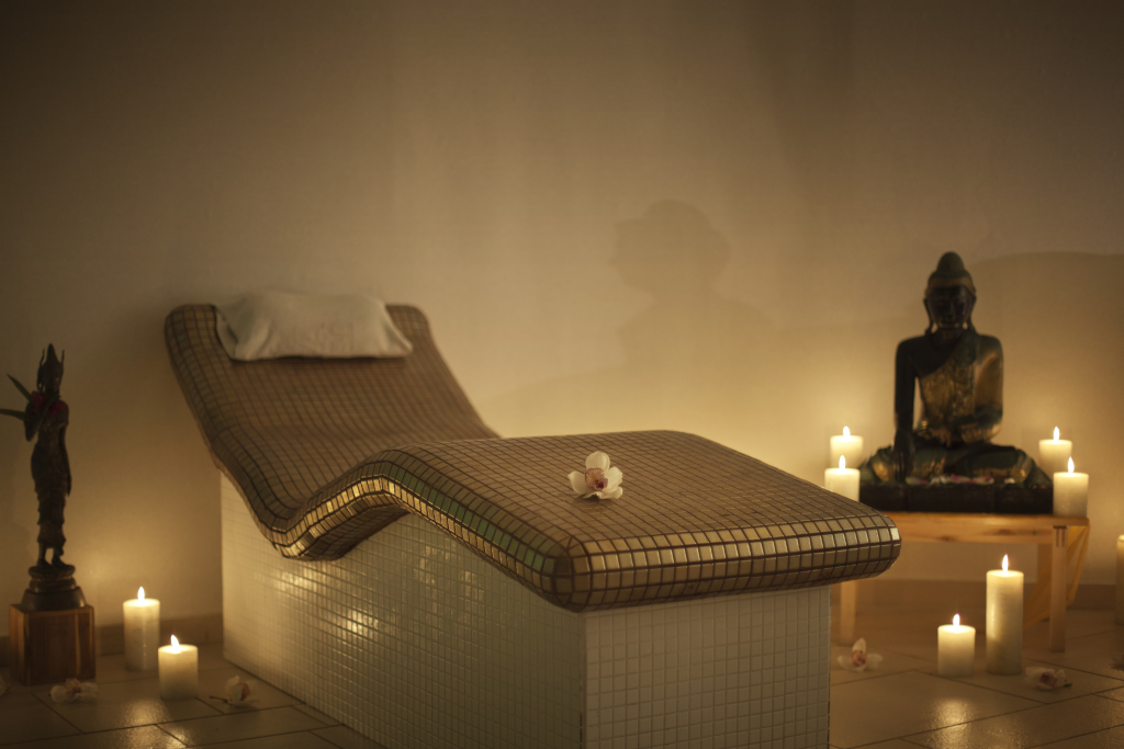 Massagetisch mit Kerzen und Statue im Spa auf Teneriffa.