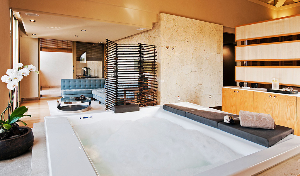 Jacuzzi im Spa-Raum mit blauem Sofa und weißer Orchidee auf Teneriffa.