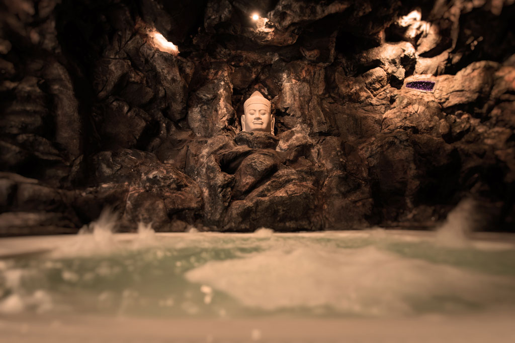 Buddha-Büste in einer felsigen Höhle mit Wasser am Fuß auf Teneriffa.