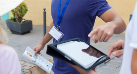 Person, die auf einen Tablet-Bildschirm auf einer Straße in Teneriffa zeigt.