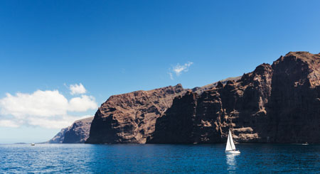 Segelboot segelt vor den Klippen von Los Gigantes, Teneriffa.