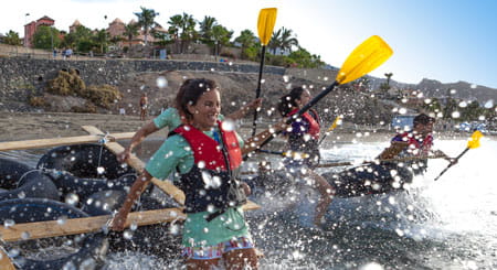 Menschen, die auf einem Floß am Strand von Los Cristianos, Teneriffa, paddeln.